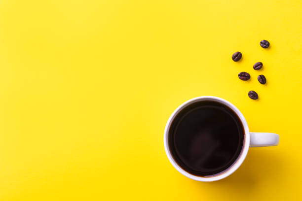 tasse de café noir avec des grains de café sur le fond jaune. vue de dessus. copiez l’espace. - coffee cup black coffee isolated photos et images de collection