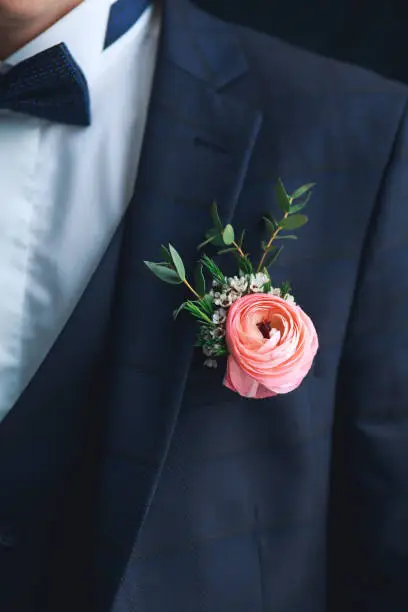 Close-up of pink ranunculus boutonniere on stylish groom
