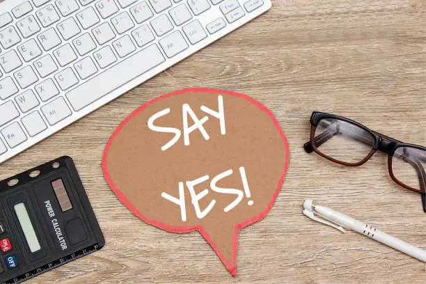 Photo of say yes on speech bubble on wooden table