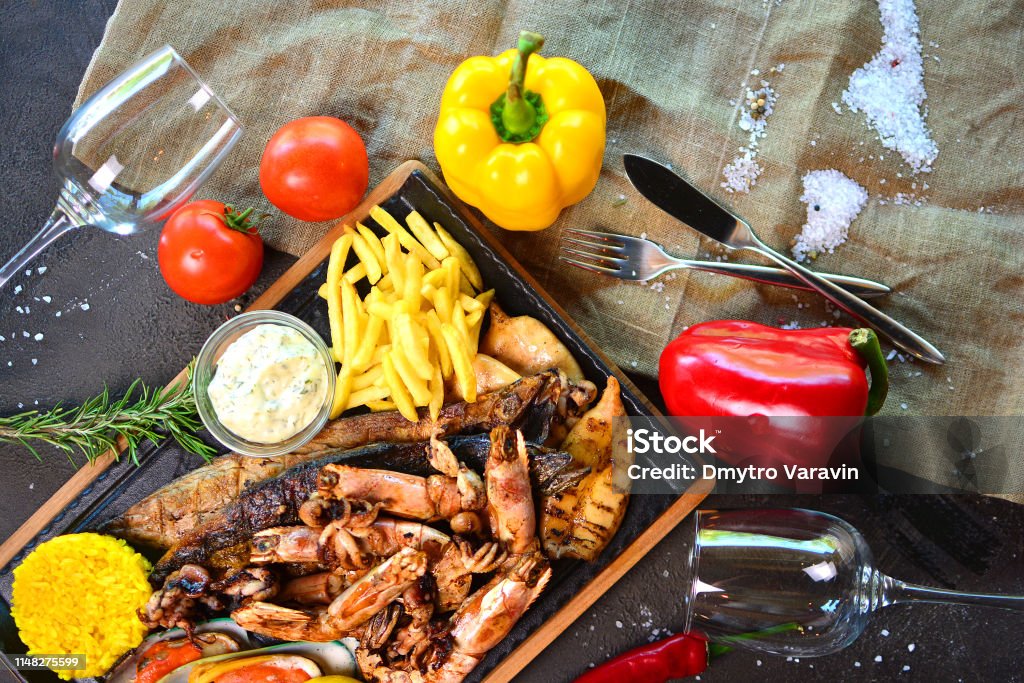 Tasty grilled seafood with French fries on a table of a restaurant cuisine. Mediterranean cuisine. Above Stock Photo