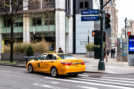 New York City, USA - April 7, 2018: Manhattan NYC buildings of midtown Herald Square Korean Town Korea Way road sign on west 32nd street with yellow taxi cab car