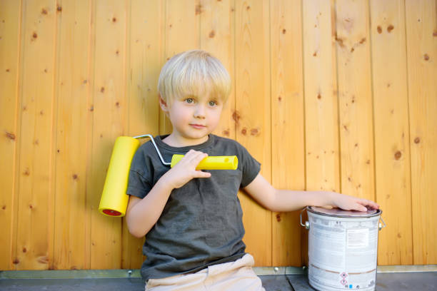 istock Child paints wooden wall by roller. Hands closeup. 1148278202