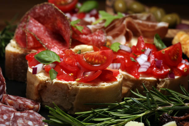 istock antipasto various appetizer. Cutting board with prosciutto, salami, cheese, bread and olives on dark wooden background 1148278700