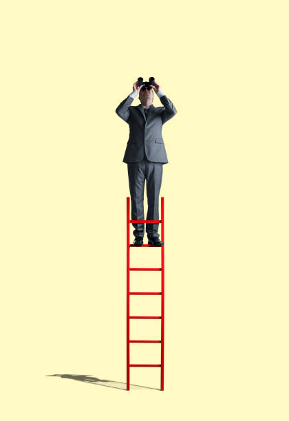 istock Businessman Standing On Ladder Looking Through Binoculars 1148279577