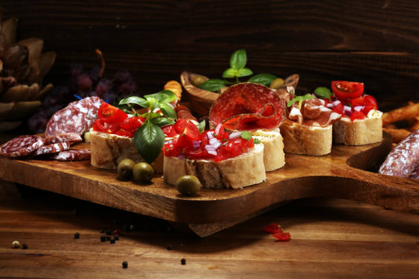 istock antipasto various appetizer. Cutting board with prosciutto, salami, cheese, bread and olives on dark wooden background 1148280468