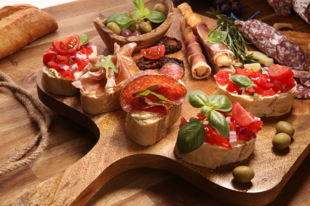 istock antipasto various appetizer. Cutting board with prosciutto, salami, cheese, bread and olives on dark wooden background 1148281115