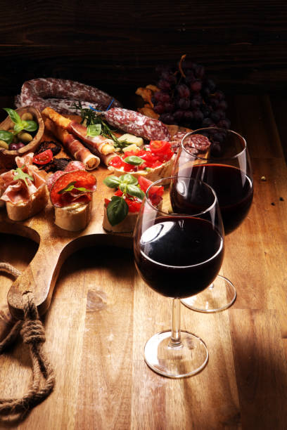 istock antipasto various appetizer. Cutting board with prosciutto, salami, cheese, bread and olives on dark wooden background 1148281175