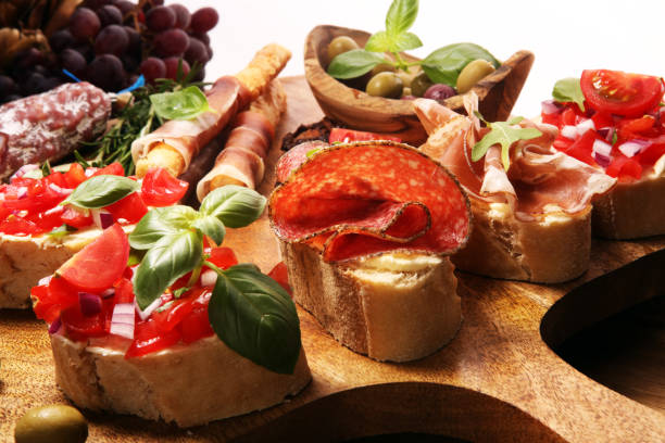 istock antipasto various appetizer. Cutting board with prosciutto, salami, cheese, bread and olives on dark wooden background 1148281359