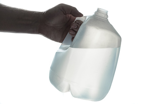 Mano sosteniendo 1 galón botella de plástico de agua potable photo