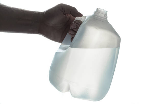 Hand holding 1 gallon plastic bottle of drinking water