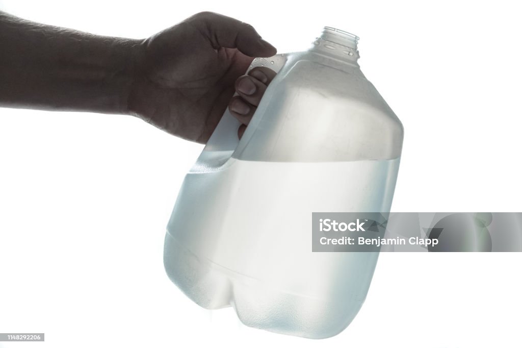 Hand holding 1 gallon plastic bottle of drinking water isolated silhouette on white background Water Stock Photo