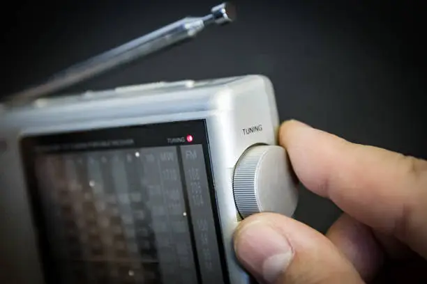 Photo of Portable radio (FM and shortwave); man's hand on tuning dial