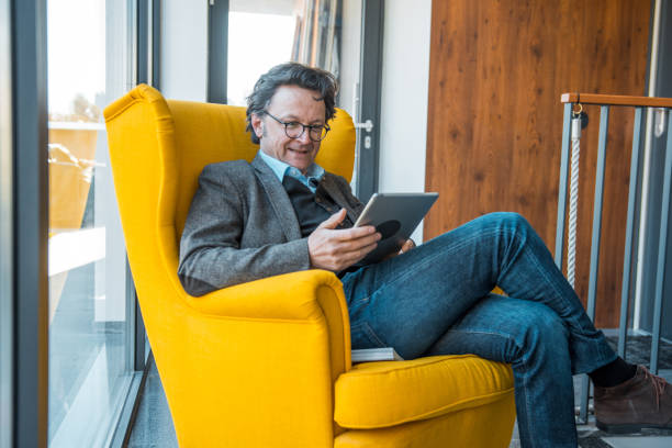 istock Mature caucasian man sitting in an armchair and using a digital tablet 1148298460