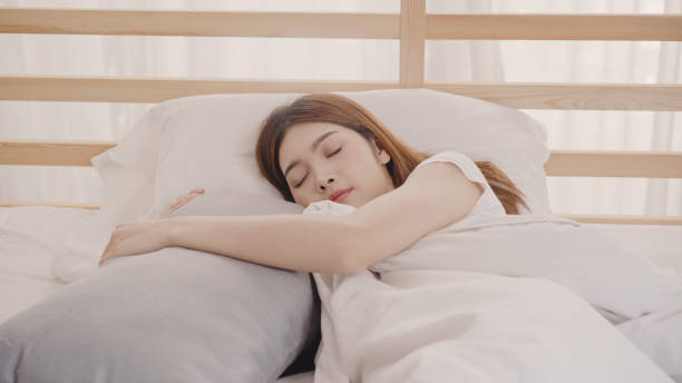 Asian woman dreaming while sleeping on bed in bedroom, Beautiful japanese female using relax time lying on bed at home. Lifestyle women using relax time at home concept. stock photo