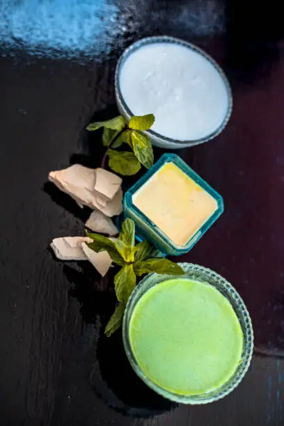 Photo of Face pack of fuller's earth or mud of multan or bleaching clay on wooden surface along with curd and mint leaves. This face pack is used to nourish,hydrates cleans skin.