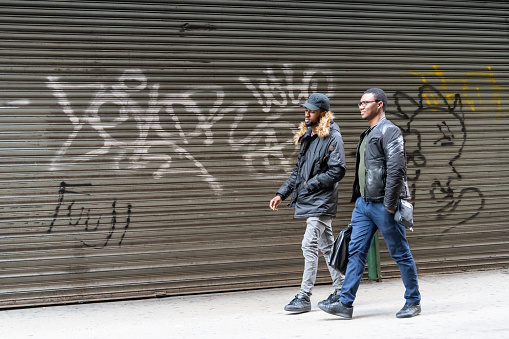 Busy people men walking on sidewalk pavement by closed garage in New York City midtown