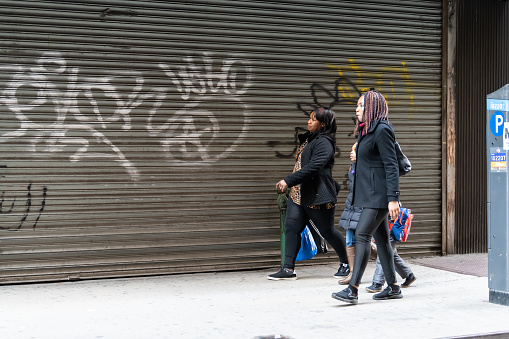 Busy people women walking on sidewalk pavement by closed garage in New York City midtown