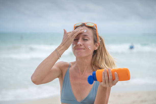 sommerzeit-junge frau am strand mit sonnencreme auf ihrem gesicht, schutz auf der haut - oahu water sand beach stock-fotos und bilder