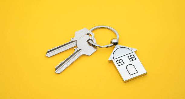 key chain with house symbol and keys on yellow background,real estate concept - key real estate key ring house key imagens e fotografias de stock