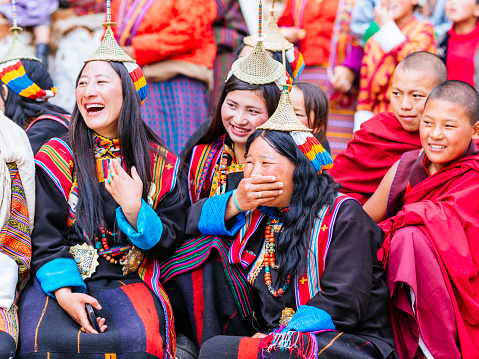 Layap women in traditional clothing are watching dancers performing in the courtyard of the Gasa dzong at the once a year Gasa Tshechu.