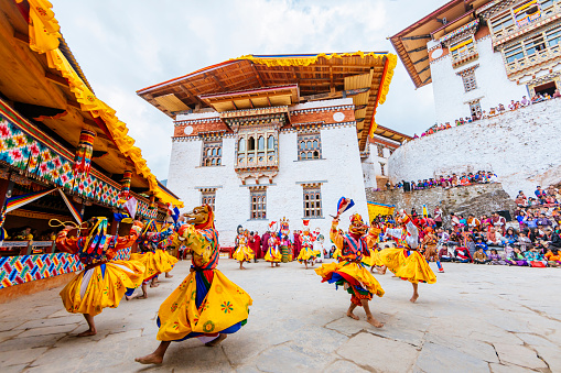 Dancers in masks and costumes are performing in the courtyard of the Gasa dzong at the once a year Gasa Tshechu