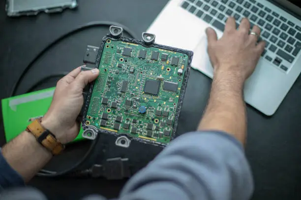 Male car mechanic doing chip tuning and  service the car with computer and software