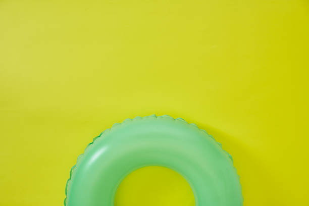 grüner aufblasbarer ring auf gelbem hintergrund. raum für text. - swimming pool inner tube toy float stock-fotos und bilder