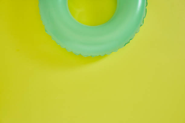 grüner aufblasbarer ring auf gelbem hintergrund. raum für text. - swimming pool inner tube toy float stock-fotos und bilder