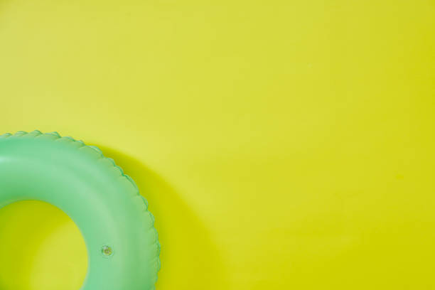 grüner aufblasbarer ring auf gelbem hintergrund. raum für text. - swimming pool inner tube toy float stock-fotos und bilder