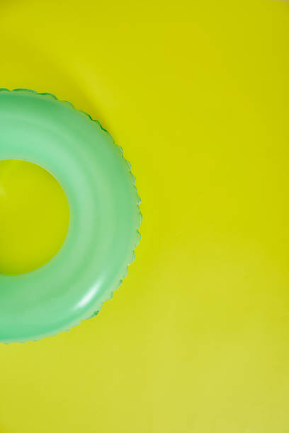 grüner aufblasbarer ring auf gelbem hintergrund. raum für text. - swimming pool inner tube toy float stock-fotos und bilder
