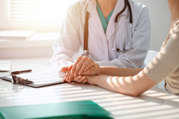 arzt beruhigt geduldige frau während des sitzes am schreibtisch in der klinik, nur die hände. medizin und bestes servicekonzept - document healthcare and medicine stethoscope history stock-fotos und bilder