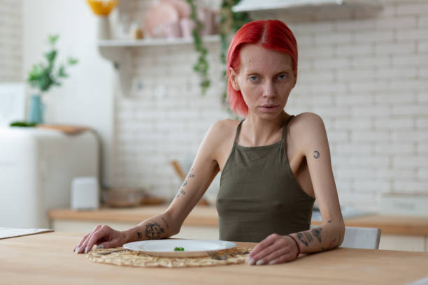 istock Red-haired anorexic woman sitting in the kitchen alone 1148339823