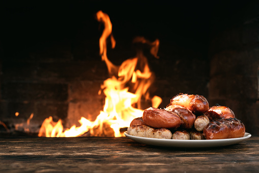 Hot sausages on a burning fire background on the kitchen table.