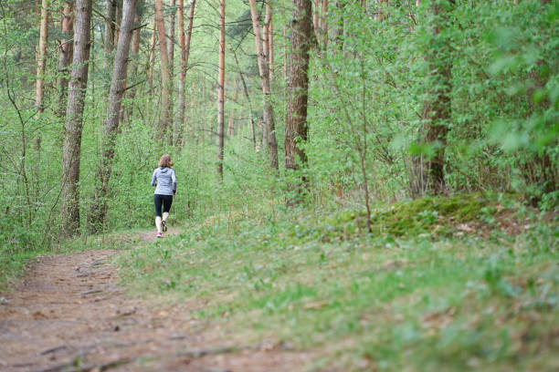 istock Athletic young woman in pink sneakers run in spring forest 1148353602