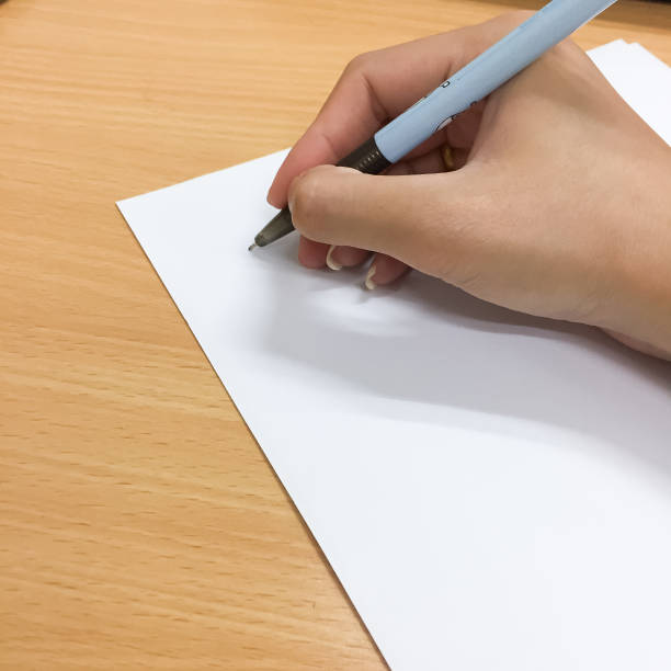 istock A woman's hand is start to write something with a black pen on a white paper. There are the empty space on the paper which can be add a text or letters or drawing. 1148354442