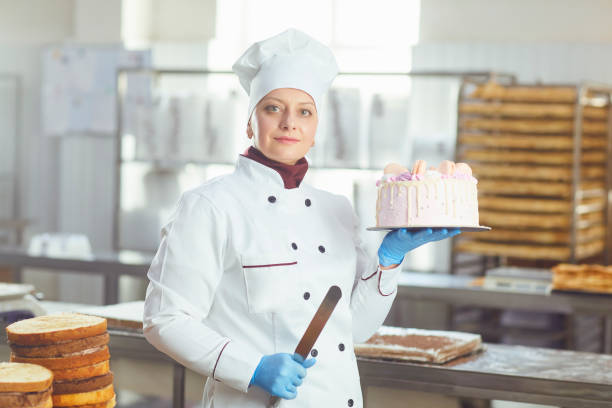 istock Confectioner with pastry cake in his hand at the bakery. 1148355462