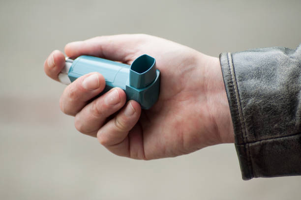 asthma aerosol in hand of man in outdoor stock photo