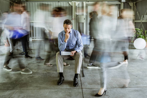 istock Pensive businessman reading reports surrounded by his colleagues in blurred motion. 1148372811