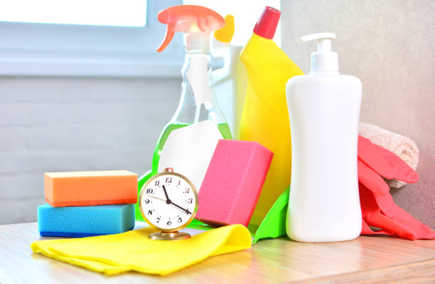 istock Cleaning service background with household chemicals and clock. 1148377956