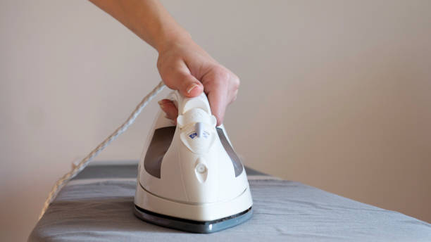 istock Woman's Hand Ironing Clothes On Ironing Board 1148380686