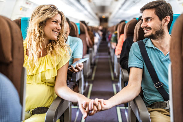 istock Happy expecting couple holding hands in a plane. 1148383757