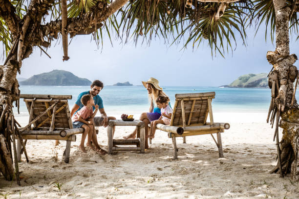 Happy family talking while relaxing on deck chairs at the beach.