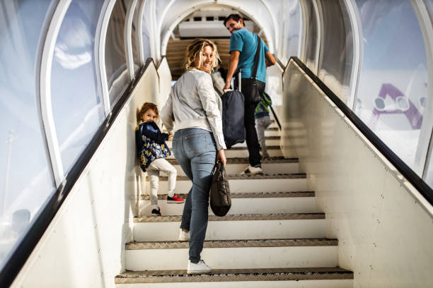 Happy family moving up the staircase towards the plane. Young happy family walking up the stairs towards the plane and turning towards the camera. flight of steps stock pictures, royalty-free photos & images