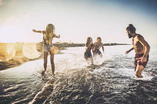 istock Happy couples having fun in the sea at sunrise. 1148385856