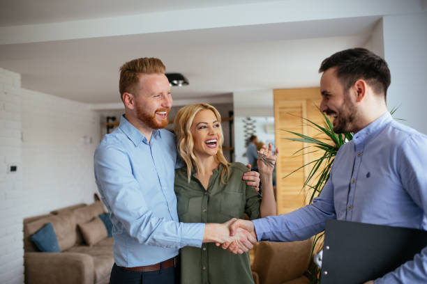 Congratulations! Portrait of financial adviser congratulating to a young couple for buying a new house. estate agency stock pictures, royalty-free photos & images