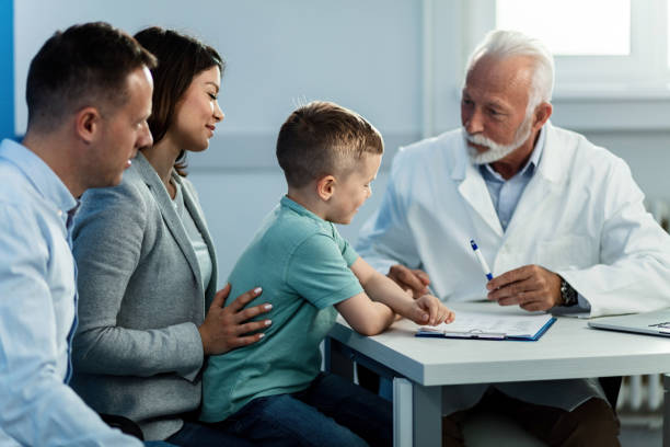 счастливый маленький мальчик с родителями на прием к педиатру. - doctor old male family стоковые фото и изображения