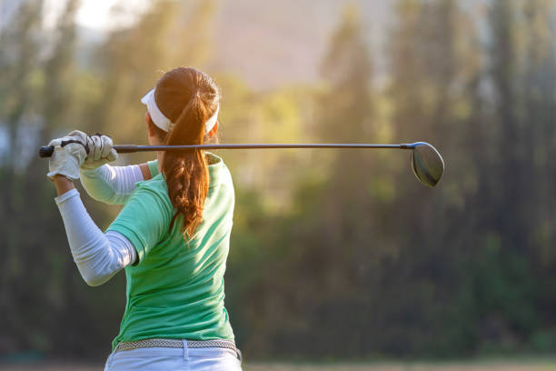 sport ist gesund. sportliche asiatin golfspieler tun golftee schaukel aus grünen sonnenuntergang abend pünktlich, sie vermutlich übt. gesunde und lifestyle-konzept. - golf green practicing sports training stock-fotos und bilder