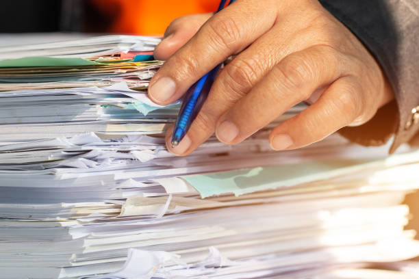 istock Businessman hands checking documents file paperwork financial market, searching information on work busy desk office. Piles of unfinished document achieves with pen for sigh. Business report  concept 1148399271