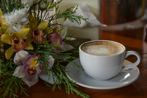 Hot coffee, ready to drink in a cup of coffee, placed beside a flower vase