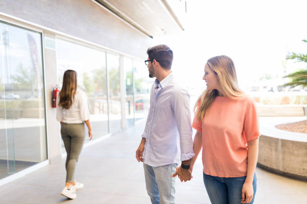 Male Tendency Of Craving For Other Women Caucasian man paying attention to other female while roaming in shopping mall with girlfriend nervous holding hands stock pictures, royalty-free photos & images